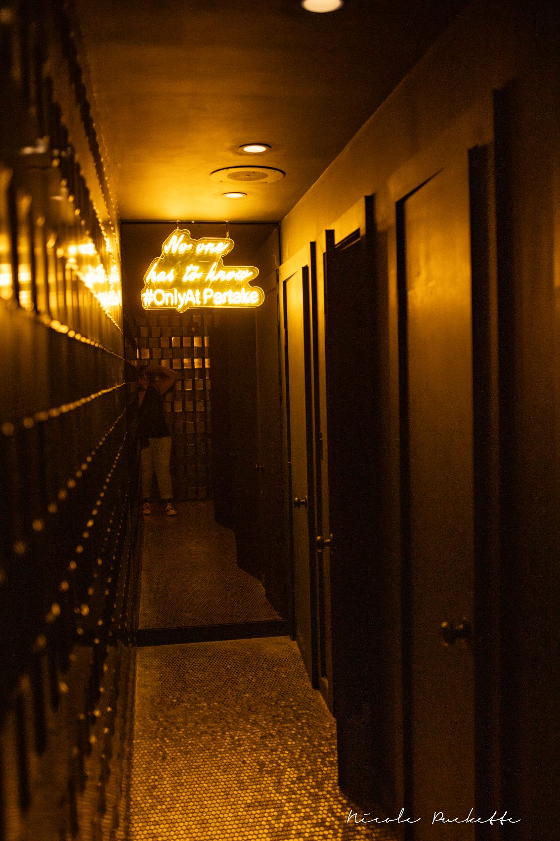 Gold neon reading no one has to know hashtag OnlyAtPartake in the Red Room hallway